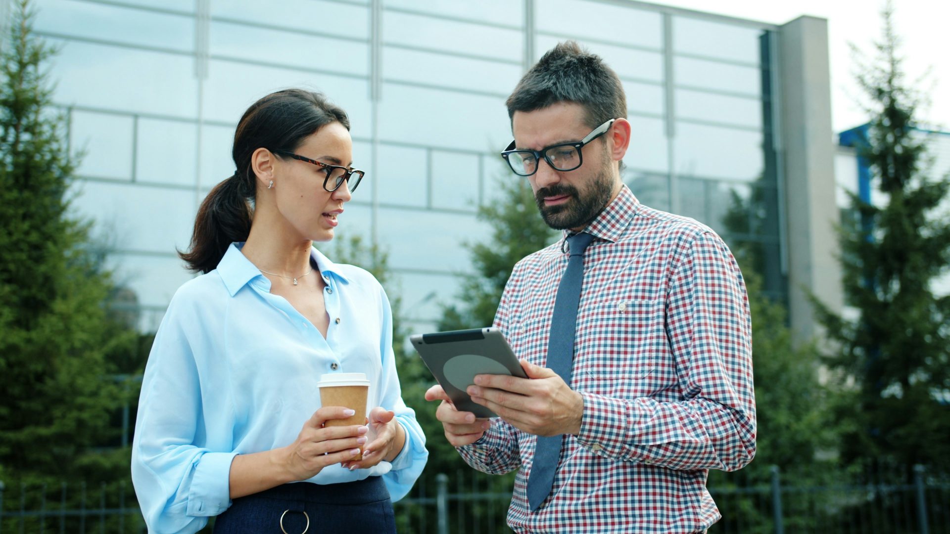 Two business people looking at a tablet outdoors.
