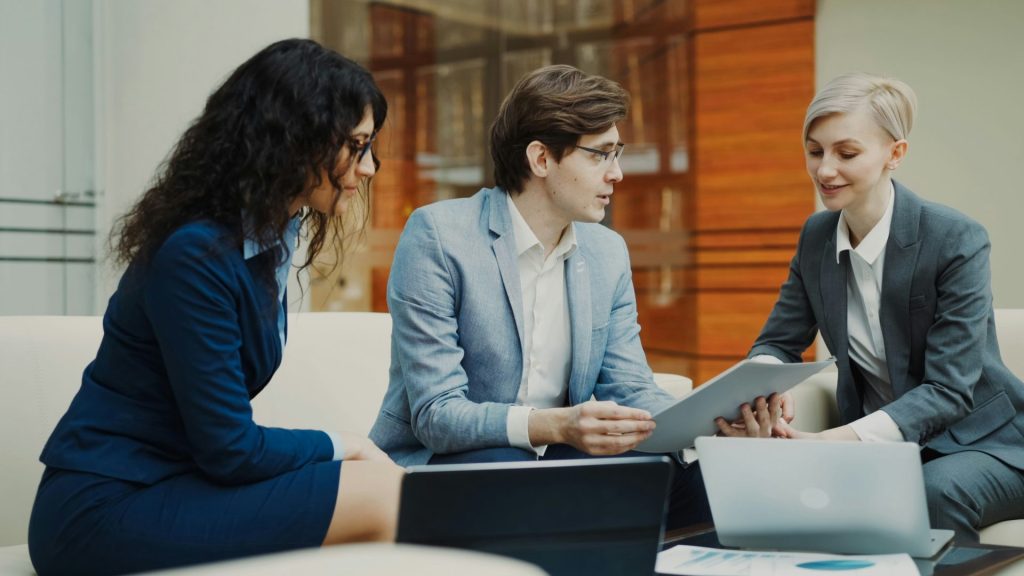 Three professionals discussing documents at a table.