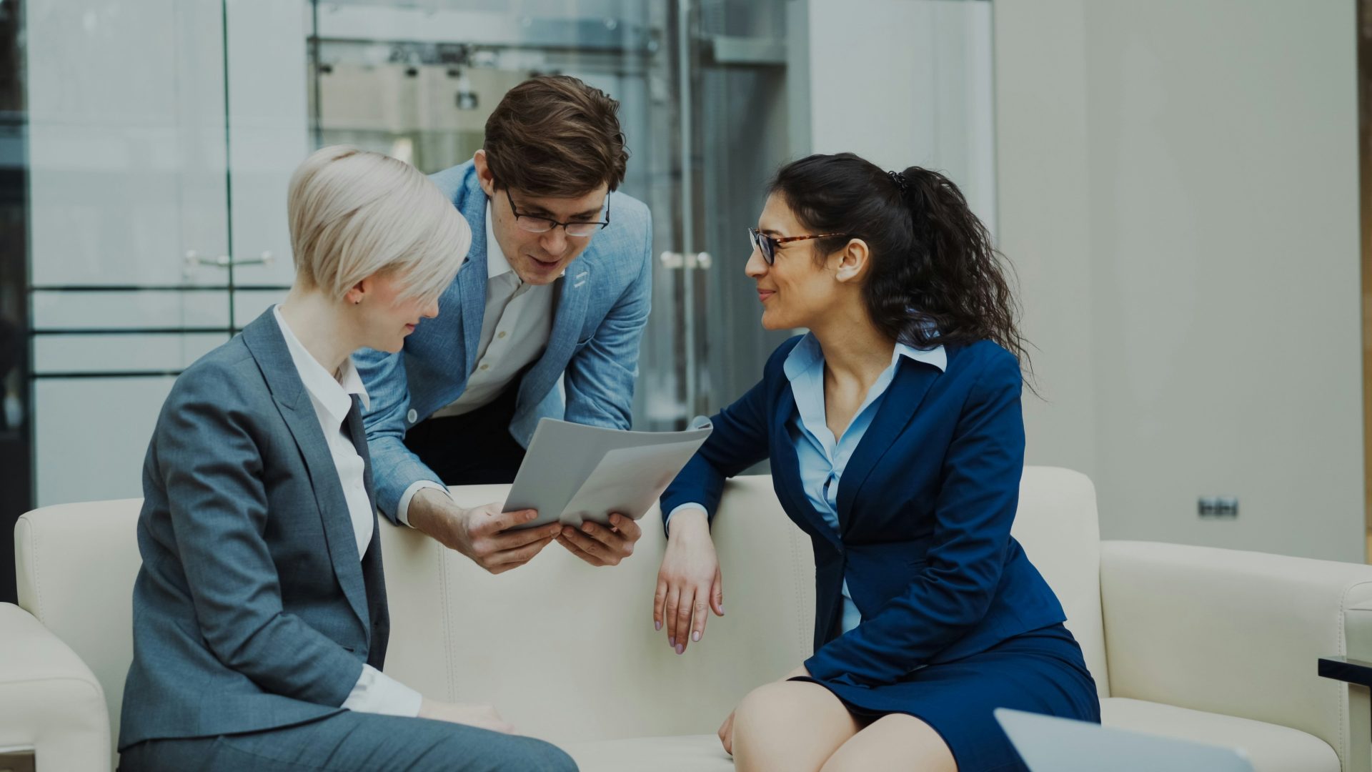 Three business people in suits discussing documents.